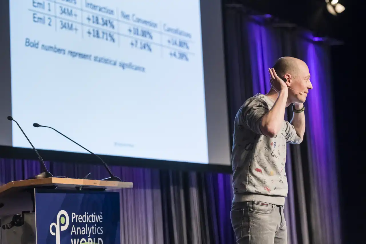 Lukas on stage with hands behind ears listening to the crowd at Predictive Analytics World in Berlin, 2017.